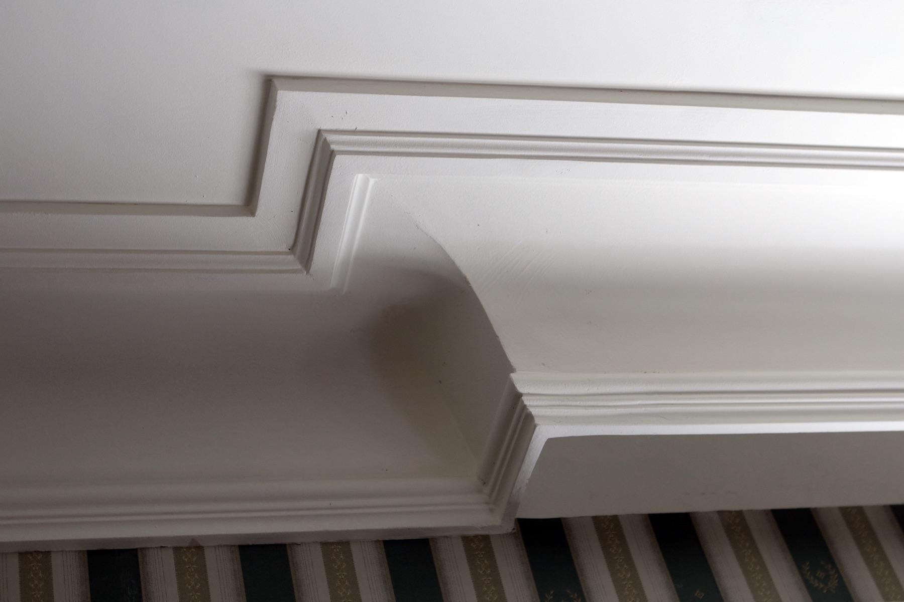 Stepped white ceiling cornice with rounded transition — minimalist classical profile